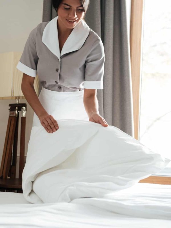 maid-setting-up-white-bed-sheet-in-hotel-room.jpg